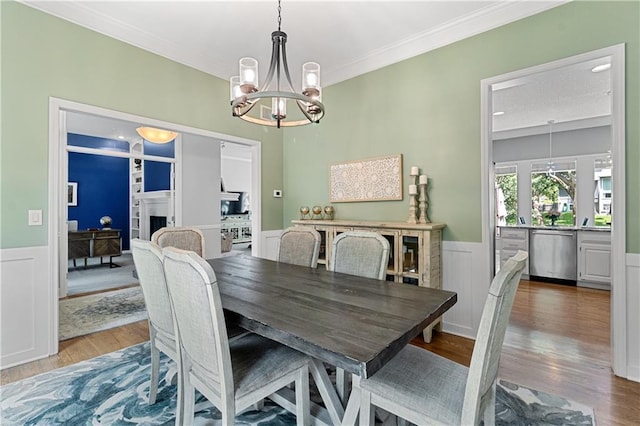 9816 W 132nd Ter, Overland Park, KS 66213 - dining space with a chandelier, wood finished floors, wainscoting, crown molding, and a fireplace