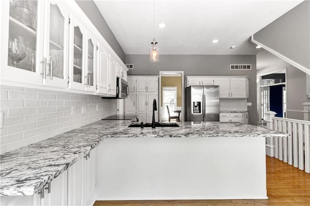 9816 W 132nd Ter, Overland Park, KS 66213 - kitchen with stainless steel appliances, a sink, a peninsula, glass insert cabinets, and tasteful backsplash