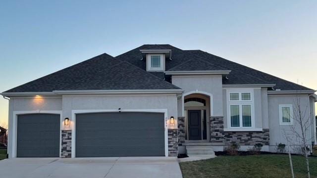 2055 NW Obrien Rd, Lees Summit, MO 64081 - view of front of home with a garage, driveway, stucco siding, stone siding, and roof with shingles