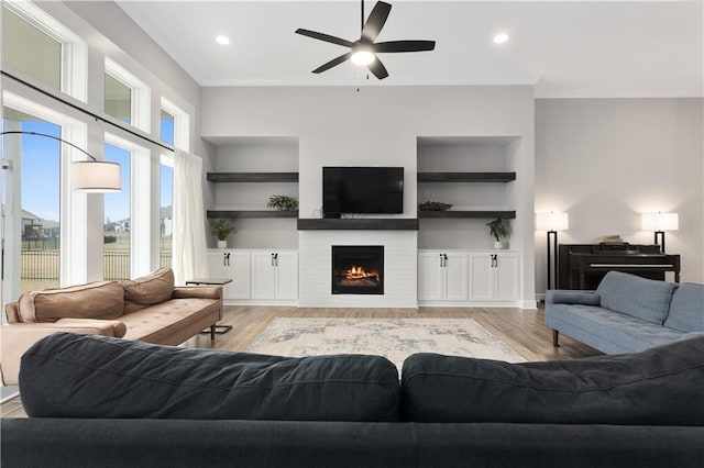 2055 NW Obrien Rd, Lees Summit, MO 64081 - living area with light wood finished floors, ornamental molding, ceiling fan, built in features, and a warm lit fireplace