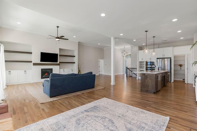 2055 NW Obrien Rd, Lees Summit, MO 64081 - living area featuring a ceiling fan, wood finished floors, built in features, a glass covered fireplace, and recessed lighting