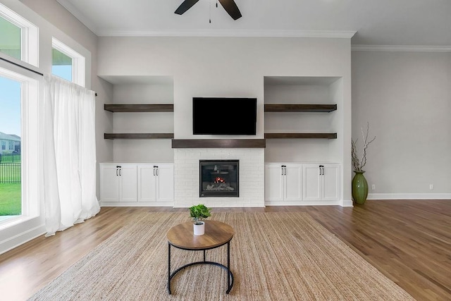 2055 NW Obrien Rd, Lees Summit, MO 64081 - living room featuring wood finished floors, ceiling fan, crown molding, a brick fireplace, and built in shelves