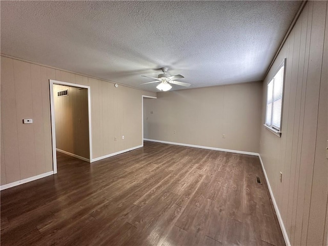 519 N Warren St, Warrensburg, MO 64093 - spare room featuring a ceiling fan, wood finished floors, baseboards, a textured ceiling, and wooden walls
