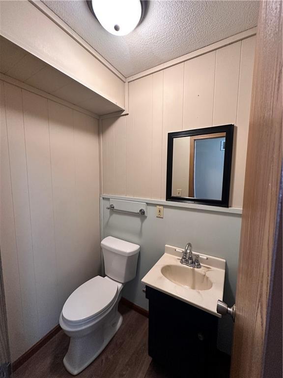 519 N Warren St, Warrensburg, MO 64093 - bathroom with toilet, wood finished floors, vanity, a textured ceiling, and baseboards