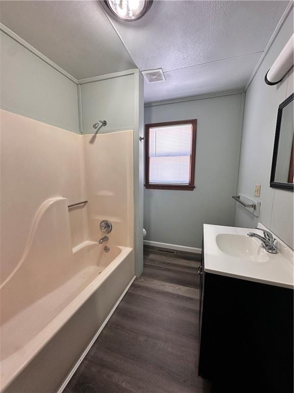 519 N Warren St, Warrensburg, MO 64093 - full bath featuring wood finished floors, toilet, vanity, a textured ceiling, and shower / washtub combination