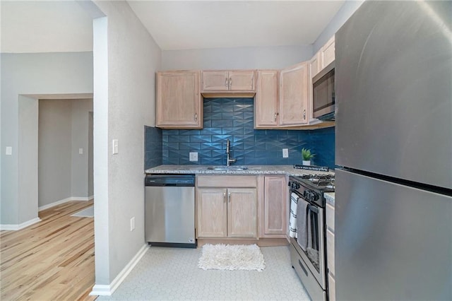412 Montgall Ave, Kansas City, MO 64124 - kitchen featuring appliances with stainless steel finishes, a sink, light brown cabinetry, tasteful backsplash, and baseboards