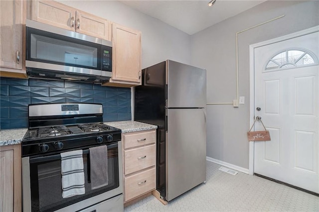 412 Montgall Ave, Kansas City, MO 64124 - kitchen featuring stainless steel appliances, light brown cabinetry, backsplash, baseboards, and light stone counters