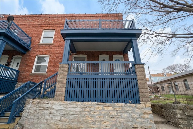 412 Montgall Ave, Kansas City, MO 64124 - view of front facade featuring stairway, brick siding, and a balcony