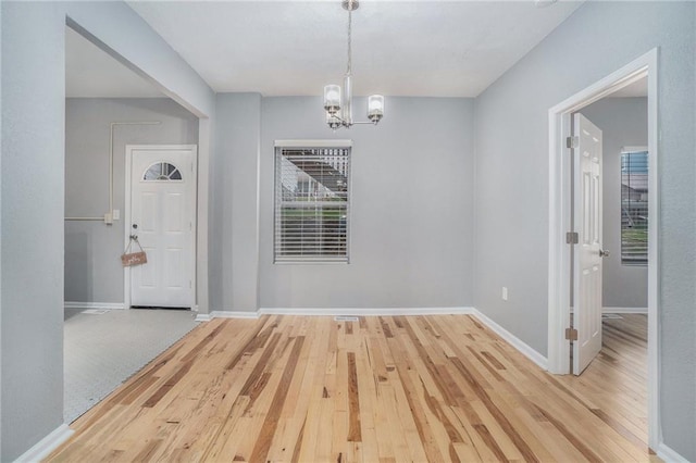 412 Montgall Ave, Kansas City, MO 64124 - unfurnished dining area with a chandelier, light wood finished floors, and baseboards