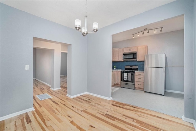 412 Montgall Ave, Kansas City, MO 64124 - kitchen featuring stainless steel appliances, light wood-style flooring, a chandelier, and baseboards
