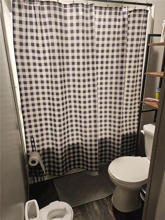 1292 255th St, Fort Scott, KS 66701 - full bathroom with toilet, wood finished floors, and a shower with curtain