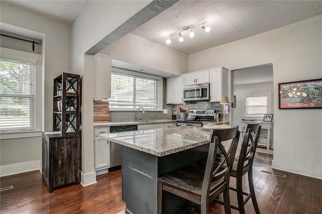 5818 W 75th St, Prairie Village, KS 66208 - kitchen featuring appliances with stainless steel finishes, light stone countertops, a breakfast bar area, decorative backsplash, and white cabinetry