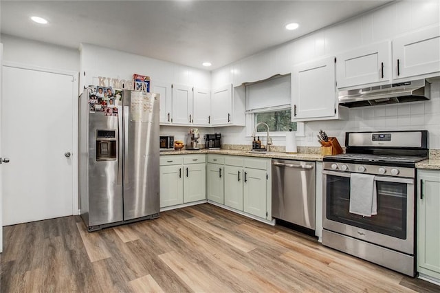 12500 E 48th Ter S, Independence, MO 64055 - kitchen with stainless steel appliances, under cabinet range hood, light wood-style flooring, a sink, and light stone counters