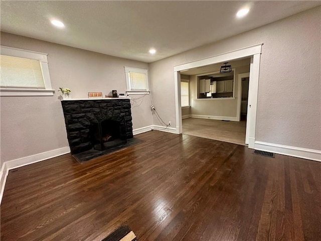 9400 E 17th St S, Independence, MO 64052 - unfurnished living room with wood finished floors, a stone fireplace, baseboards, and recessed lighting
