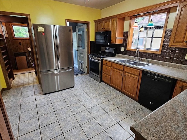 kitchen featuring black appliances, a sink, tasteful backsplash, light tile patterned flooring, and brown cabinets