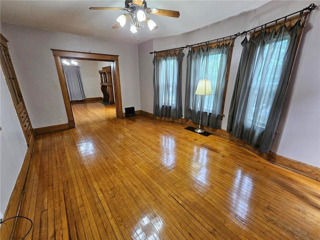 unfurnished room featuring ceiling fan, hardwood / wood-style flooring, and baseboards