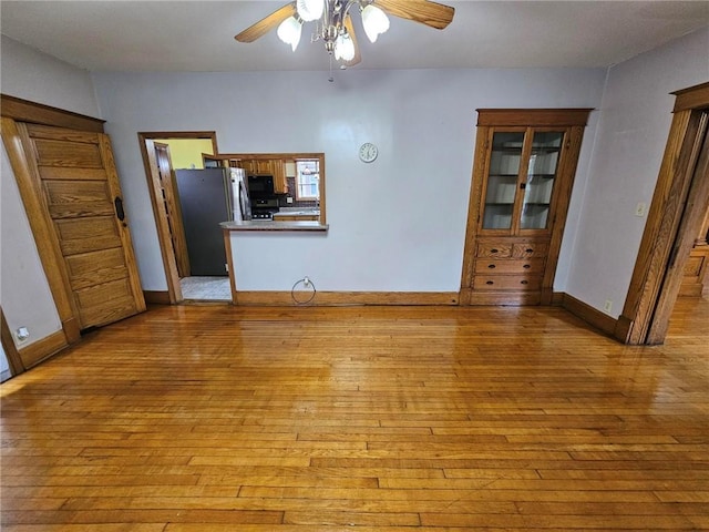 unfurnished room featuring light wood-style floors, ceiling fan, and baseboards