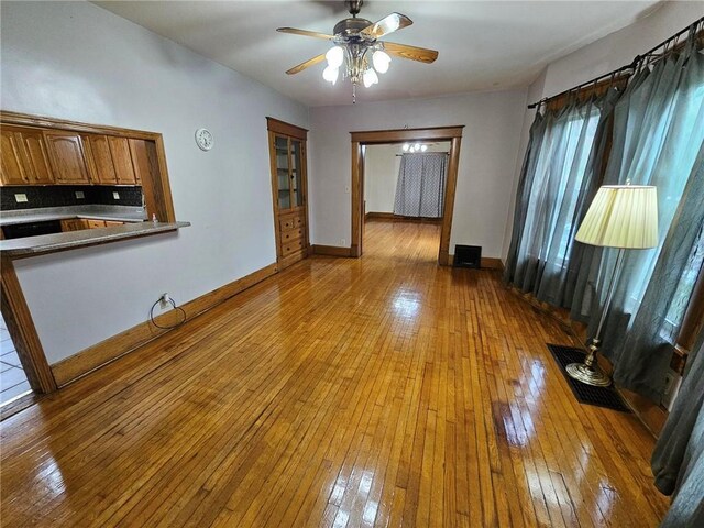 unfurnished living room featuring hardwood / wood-style flooring, a ceiling fan, and baseboards