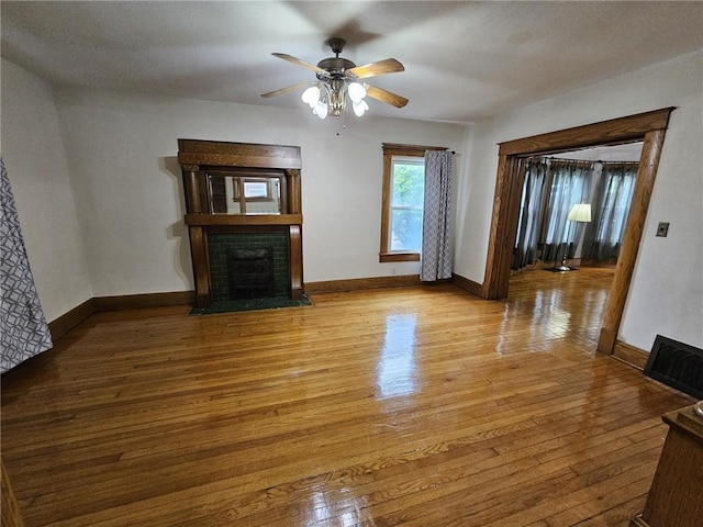 unfurnished living room with a fireplace with flush hearth, wood finished floors, ceiling fan, and baseboards