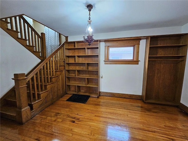 stairs with hardwood / wood-style floors and a chandelier