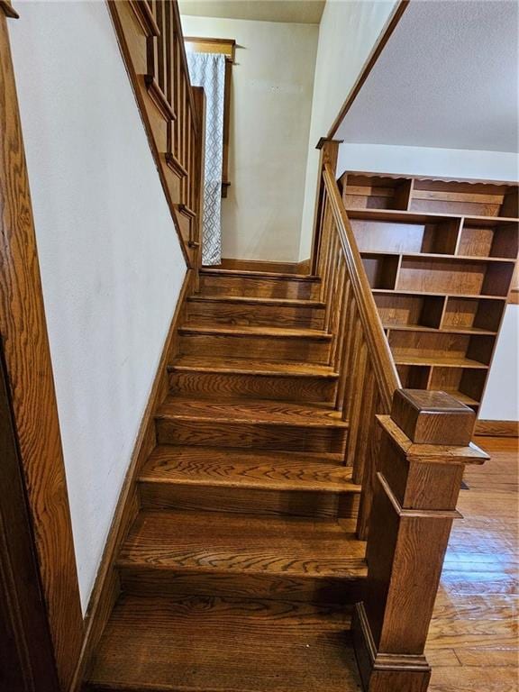 stairway featuring hardwood / wood-style floors and baseboards