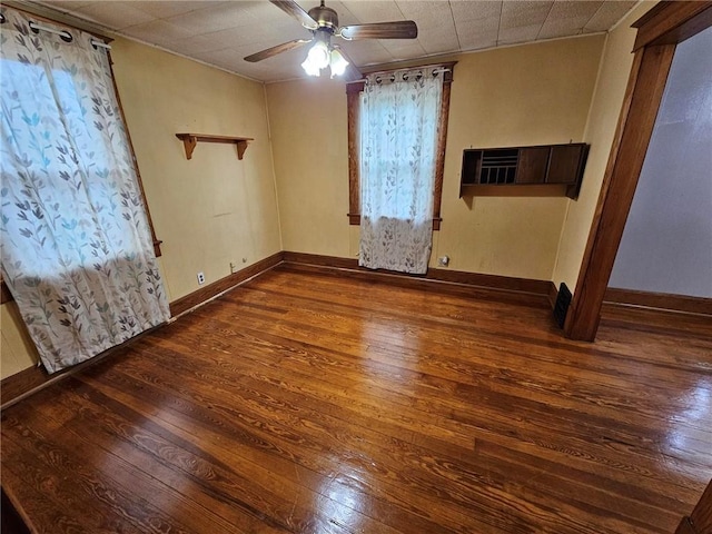unfurnished room with hardwood / wood-style flooring, a ceiling fan, and baseboards
