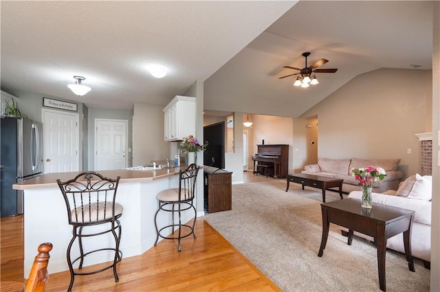 3100 Clarendon Rd, Sedalia, MO 65301 - kitchen featuring freestanding refrigerator, white cabinets, a peninsula, light wood-type flooring, and a ceiling fan
