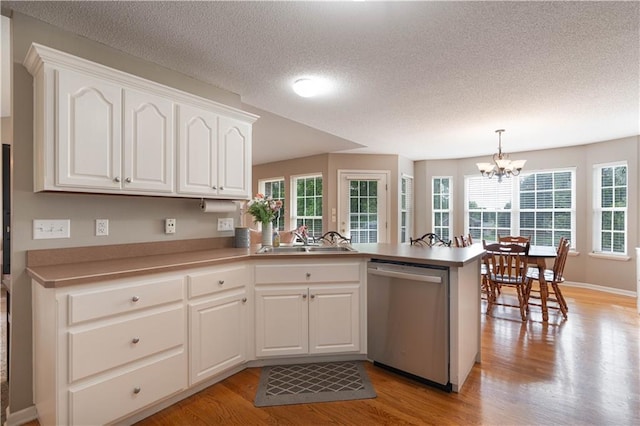 3100 Clarendon Rd, Sedalia, MO 65301 - kitchen with dishwasher, a sink, a peninsula, light wood-type flooring, and a textured ceiling