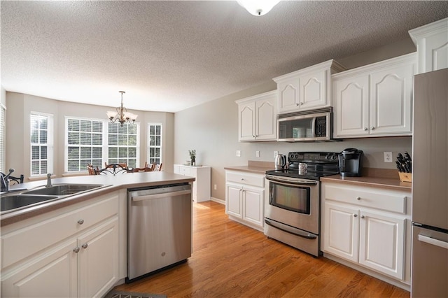 3100 Clarendon Rd, Sedalia, MO 65301 - kitchen featuring appliances with stainless steel finishes, a sink, a chandelier, white cabinets, and a textured ceiling