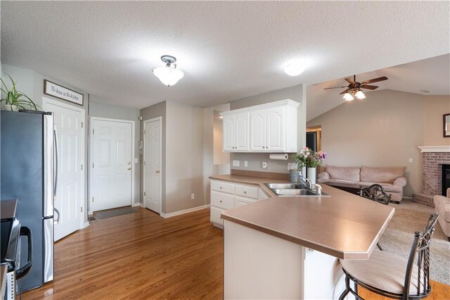 3100 Clarendon Rd, Sedalia, MO 65301 - kitchen with a sink, freestanding refrigerator, a peninsula, white cabinets, and light wood-style floors