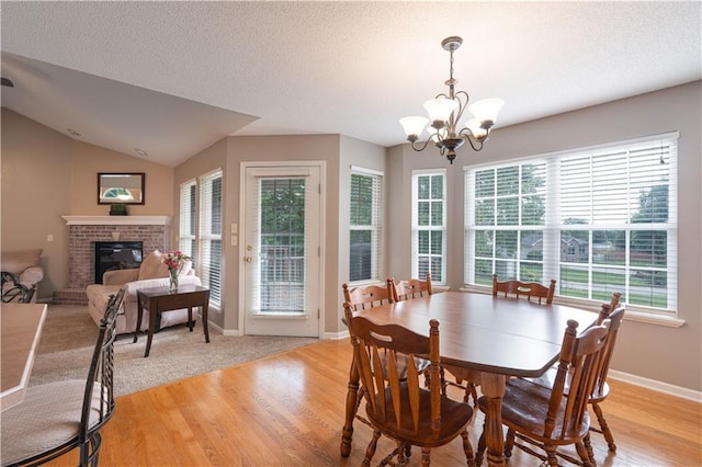 3100 Clarendon Rd, Sedalia, MO 65301 - dining space with a brick fireplace, a chandelier, light wood-style floors, baseboards, and a textured ceiling