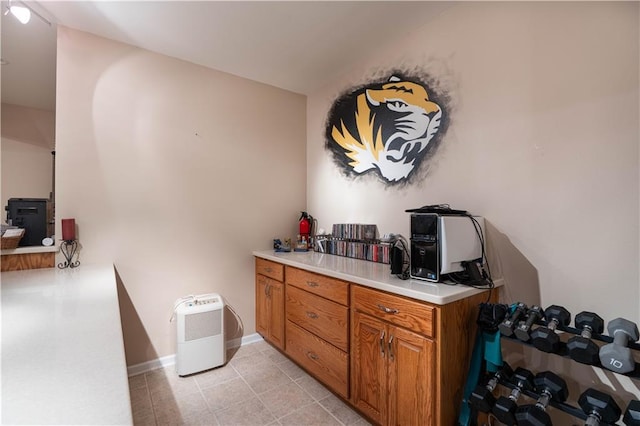 3100 Clarendon Rd, Sedalia, MO 65301 - kitchen featuring brown cabinetry, light countertops, light tile patterned floors, and baseboards