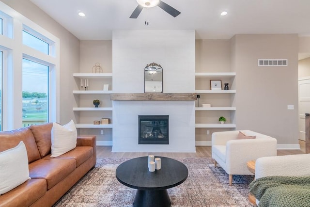 16729 Pinehurst Dr, Basehor, KS 66007 - living area with wood finished floors, a ceiling fan, a tiled fireplace, built in features, and recessed lighting