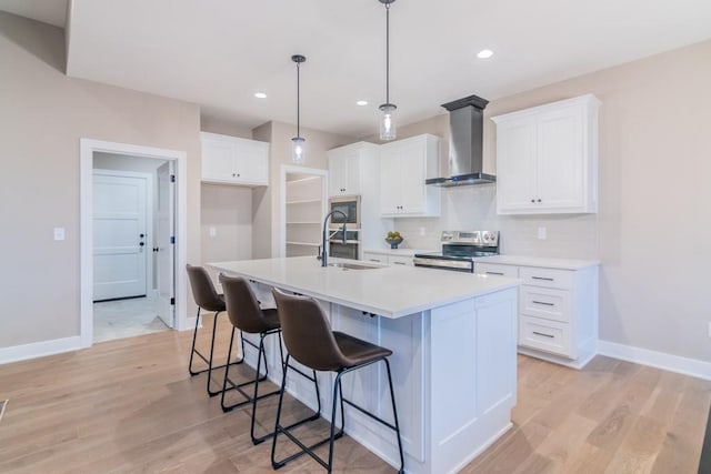 16729 Pinehurst Dr, Basehor, KS 66007 - kitchen featuring wall chimney exhaust hood, a sink, stainless steel range with electric cooktop, baseboards, and a kitchen island with sink