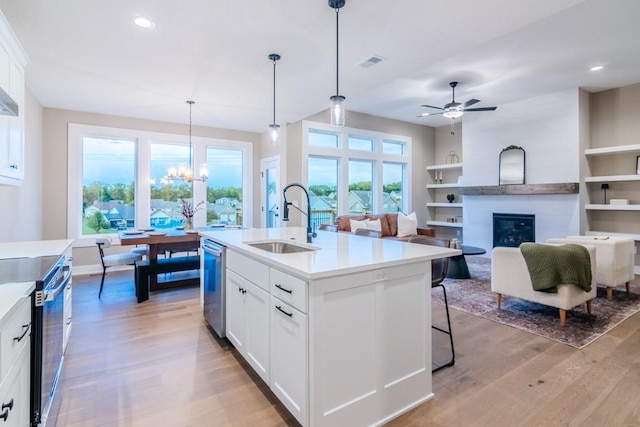 16729 Pinehurst Dr, Basehor, KS 66007 - kitchen with a sink, stainless steel appliances, light wood-style floors, a large fireplace, and a chandelier