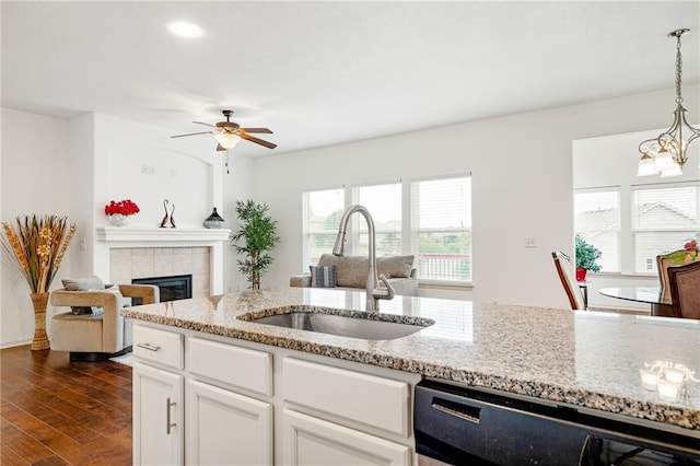 23713 W 88th St, Lenexa, KS 66227 - kitchen featuring a sink, a ceiling fan, a tiled fireplace, decorative light fixtures, and light stone counters