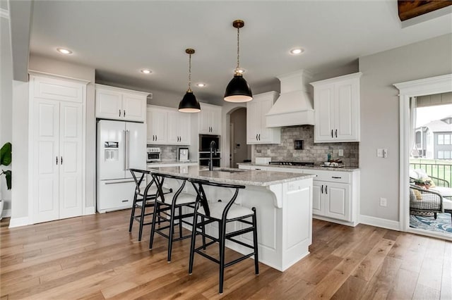 15670 W 165th Ter, Olathe, KS 66062 - kitchen with white fridge with ice dispenser, custom exhaust hood, a sink, gas cooktop, and light wood-style floors