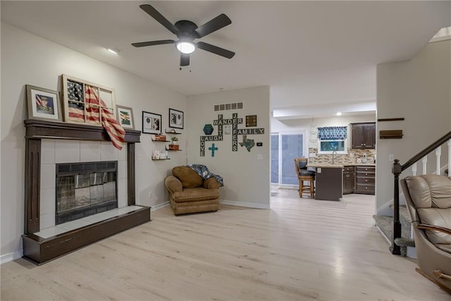 21830 S Race St, Spring Hill, KS 66083 - living area featuring light wood-style flooring, a tile fireplace, stairs, ceiling fan, and baseboards