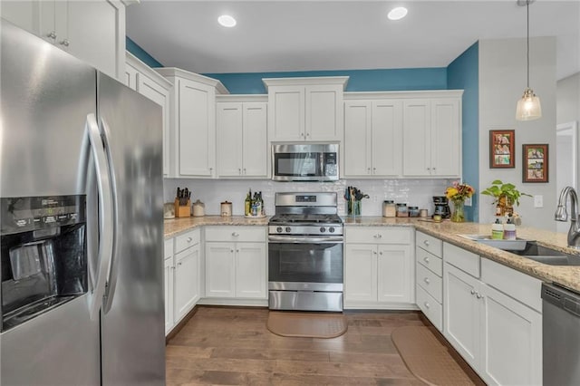 1302 N 159th St, Basehor, KS 66007 - kitchen with appliances with stainless steel finishes, dark wood-style floors, white cabinets, a sink, and light stone counters