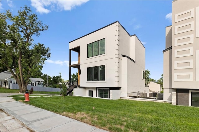 4550 Bell St, Kansas City, MO 64111 - view of side of property featuring stairway, a lawn, and stucco siding