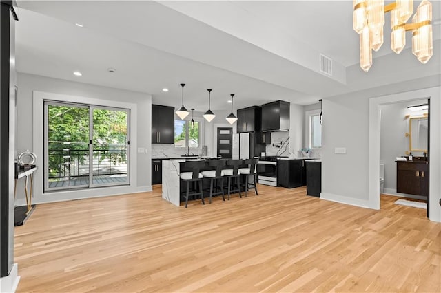 4550 Bell St, Kansas City, MO 64111 - kitchen with dark cabinetry, decorative backsplash, a breakfast bar area, light wood-style flooring, and recessed lighting