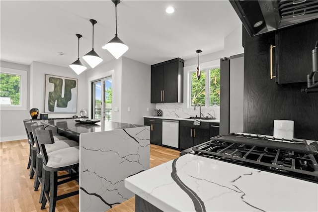 4550 Bell St, Kansas City, MO 64111 - kitchen with dark cabinets, dishwasher, range hood, plenty of natural light, and recessed lighting