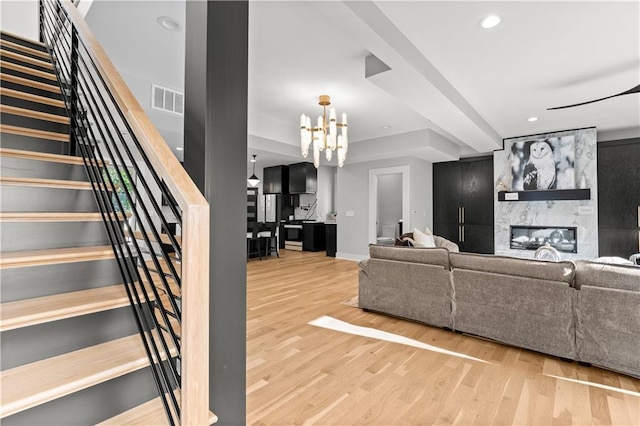 4550 Bell St, Kansas City, MO 64111 - living area featuring wood finished floors, a large fireplace, a chandelier, stairs, and recessed lighting