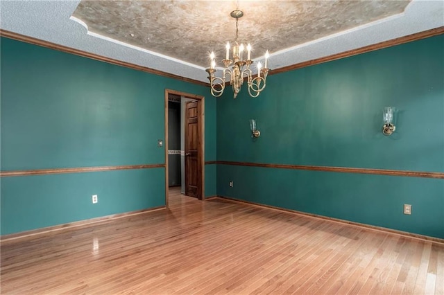 10404 Flint St, Overland Park, KS 66214 - empty room featuring a textured ceiling, a chandelier, wood finished floors, baseboards, and a tray ceiling
