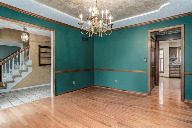 10404 Flint St, Overland Park, KS 66214 - empty room featuring a chandelier, wood finished floors, stairs, a textured ceiling, and baseboards