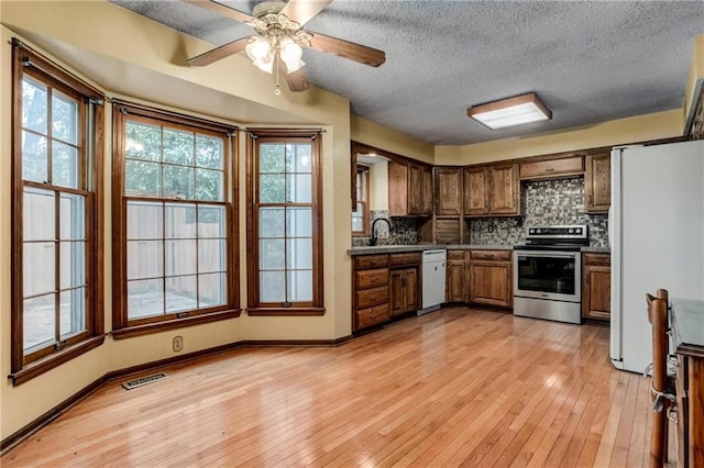 10404 Flint St, Overland Park, KS 66214 - kitchen with white appliances, tasteful backsplash, light wood-type flooring, a textured ceiling, and a ceiling fan