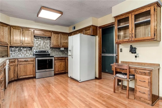10404 Flint St, Overland Park, KS 66214 - kitchen with stainless steel electric range, white refrigerator with ice dispenser, light wood finished floors, brown cabinets, and a textured ceiling