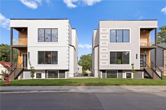 4544 Bell St, Kansas City, MO 64111 - view of front of property with stairway, a balcony, stucco siding, and a front lawn
