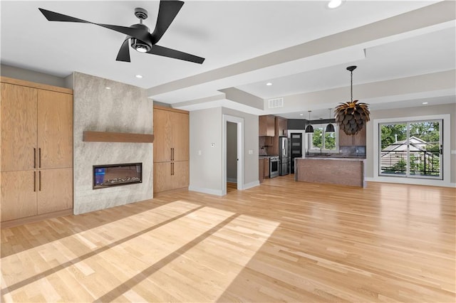 4544 Bell St, Kansas City, MO 64111 - unfurnished living room featuring a fireplace, light wood-type flooring, a ceiling fan, and recessed lighting
