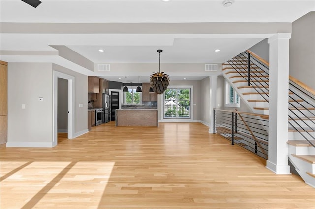 4544 Bell St, Kansas City, MO 64111 - unfurnished living room with light wood-type flooring, stairway, and recessed lighting